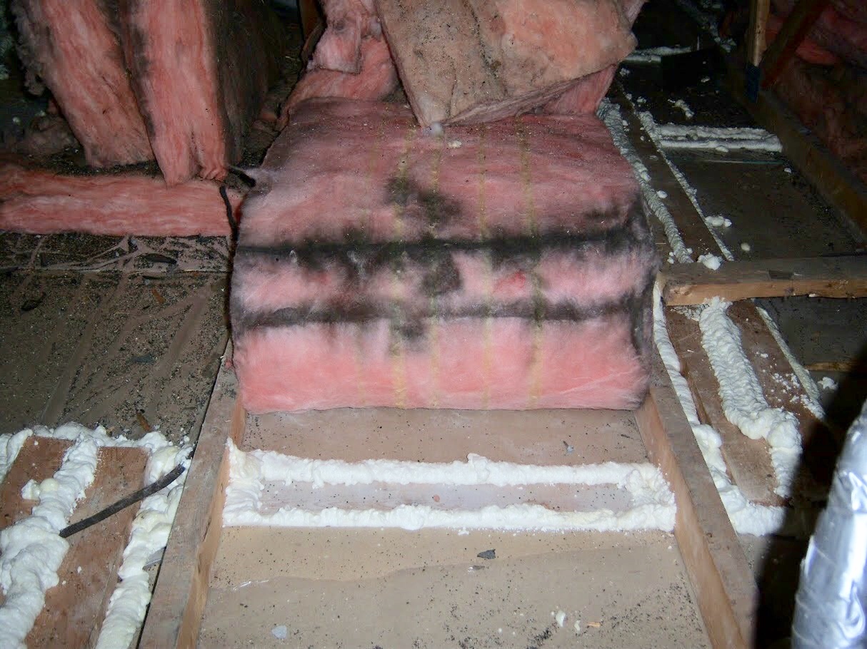 Attic insulation lifted to reveal sealed gaps around framing and penetrations